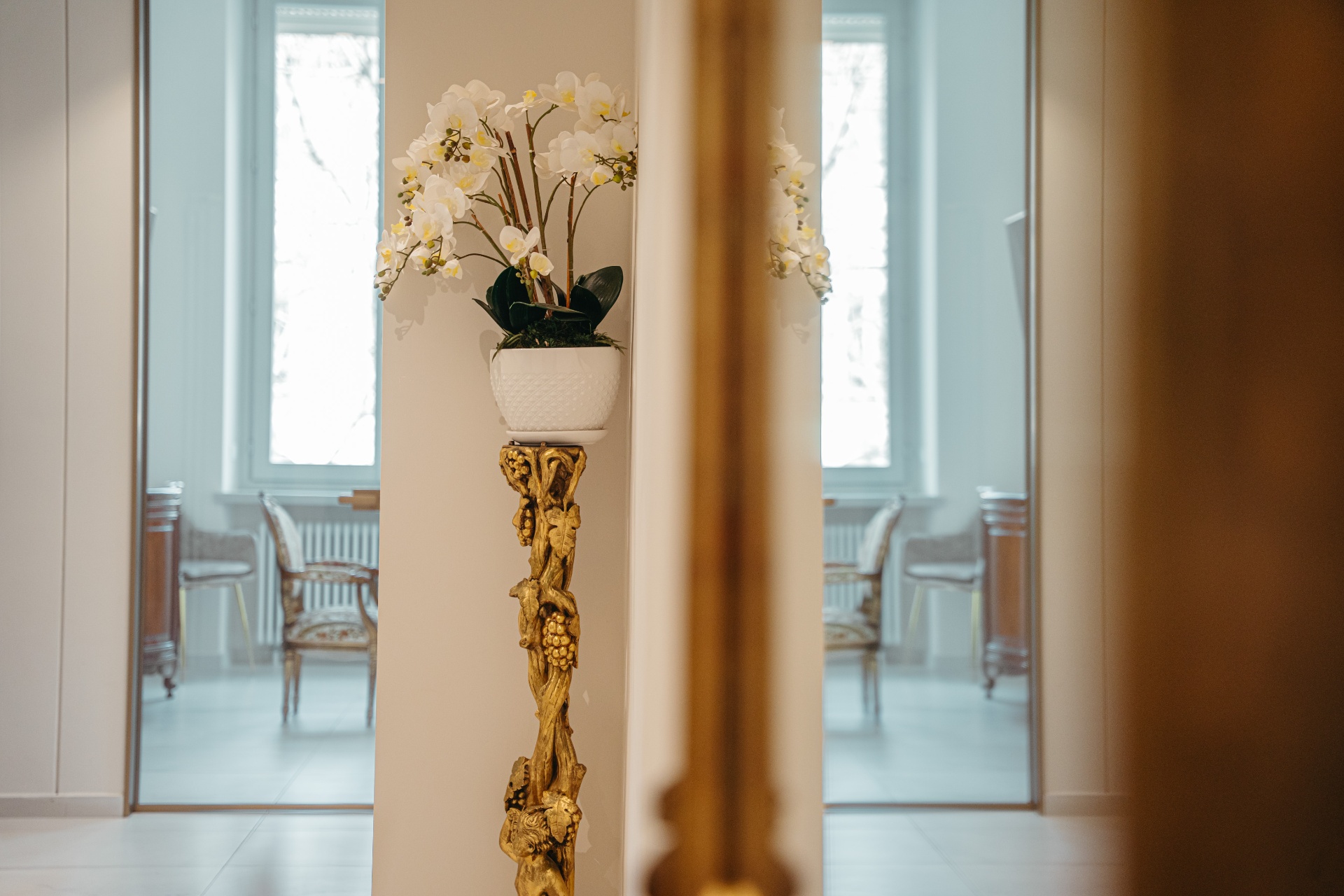 Orchidea bianca su piedistallo dorato con corridoio dello Studio riflesso in specchio