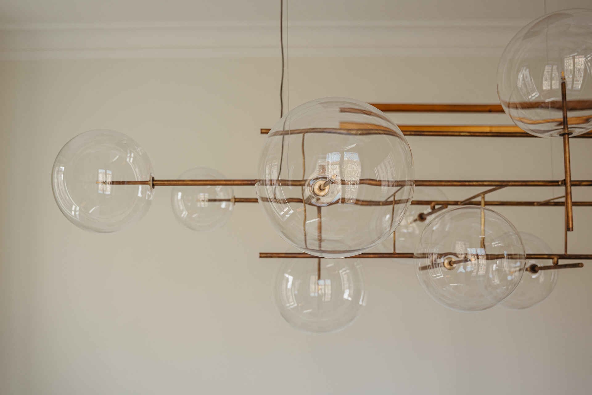 Lampadario contemporaneo con sfere di vetro trasparente e struttura in ottone brunito nello Studio Saglietti Bianco