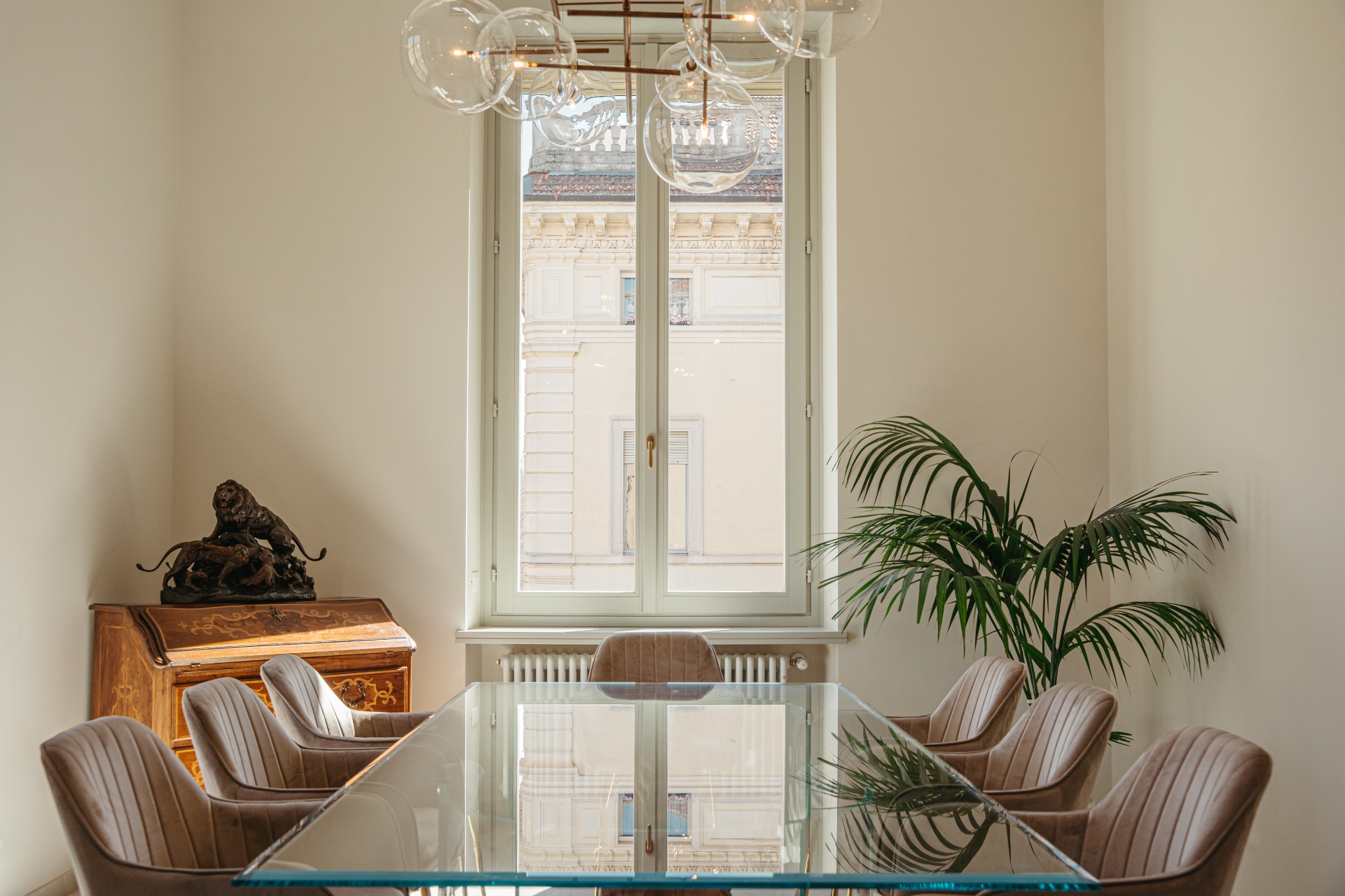 Sala riunioni dello studio Saglietti Bianco con tavolo di cristallo, finestra sulla città e lampadario